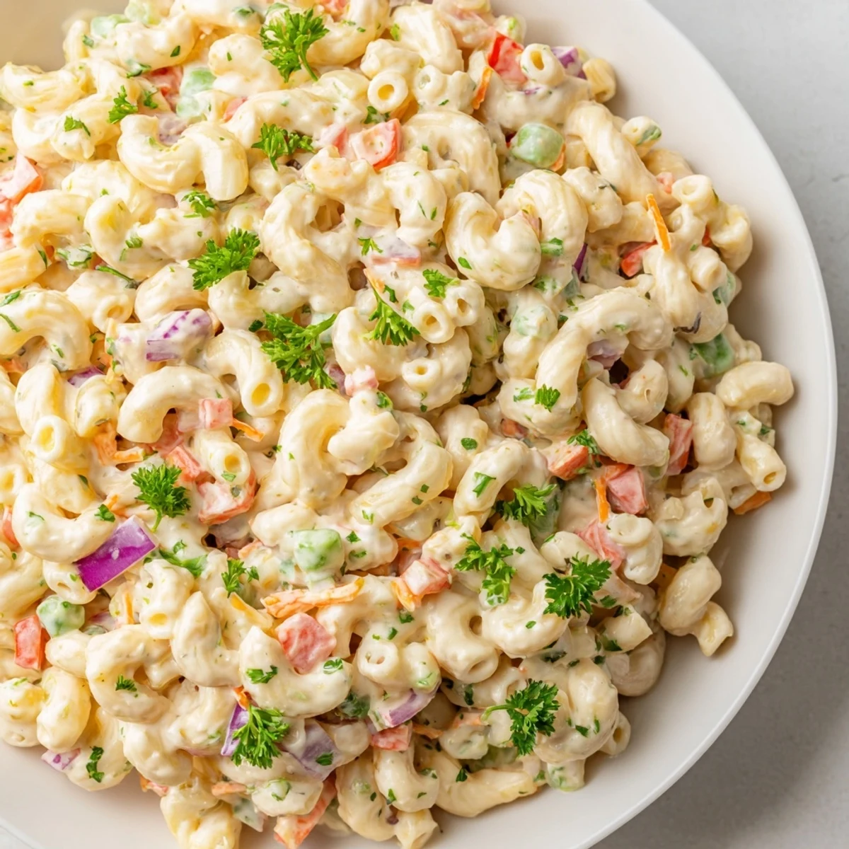 Creamy macaroni salad, chilled and ready, featuring colorful veggies, ideal for picnics.
