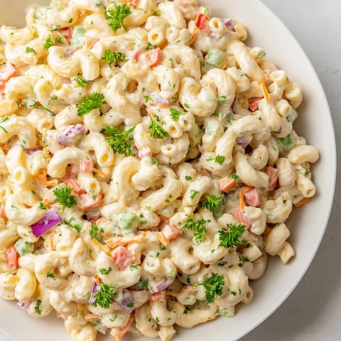 Creamy macaroni salad, chilled and ready, featuring colorful veggies, ideal for picnics.
