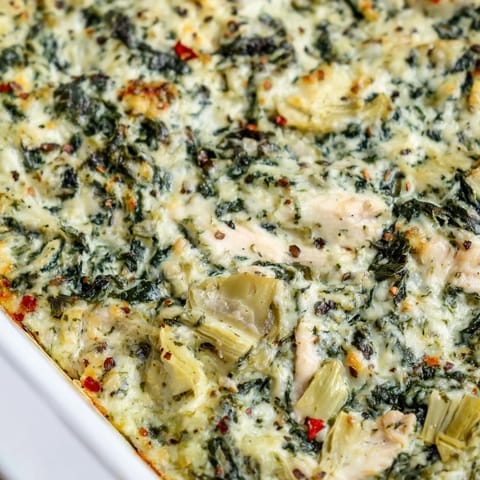 Fork-tender chicken breasts in a creamy spinach and artichoke topping, ready to serve with a crisp side salad.