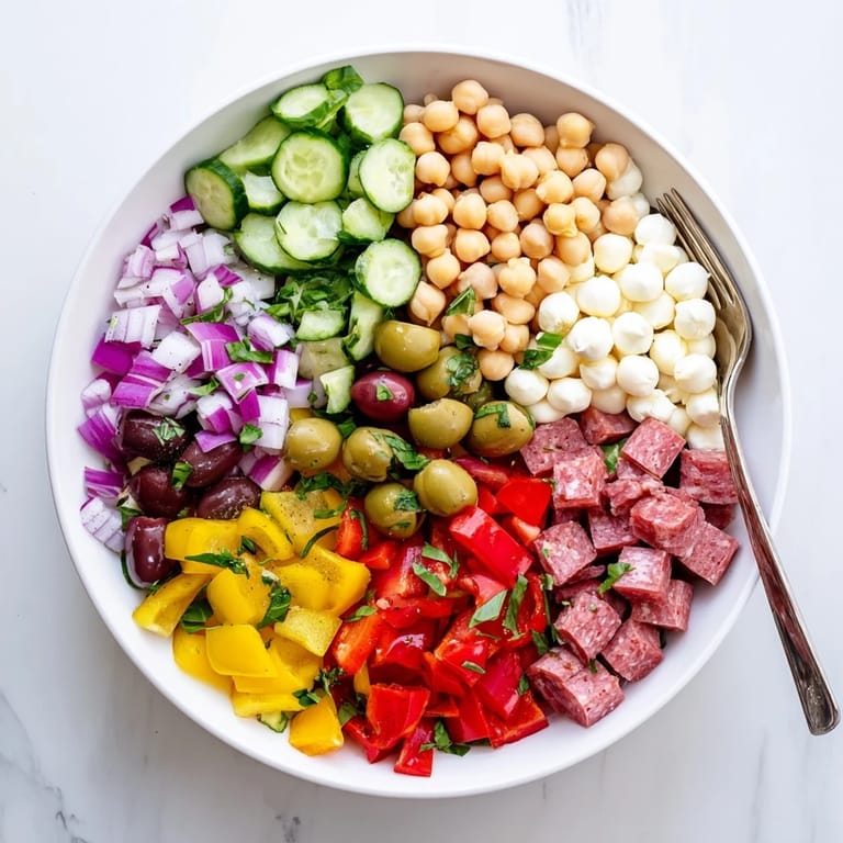Refreshing Crunchy Antipasto Chopped Salad on a white plate, featuring crisp cucumbers, peppers, and olives.