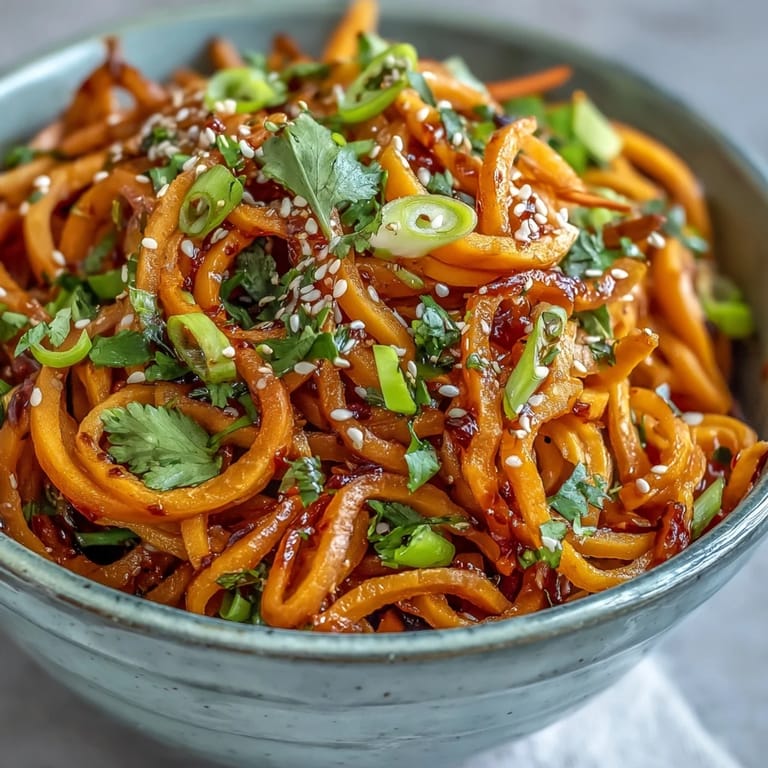 Savory Gochujang Swede Noodles plated with julienned carrots and green onions, ready to serve for a comforting vegan dinner.