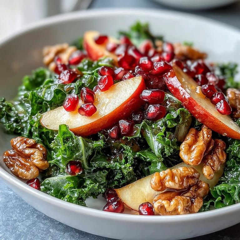 Colorful kale pomegranate bowl featuring juicy seeds, sliced apples, and toasted walnuts, perfect for a healthy vegetarian lunch or side dish.  