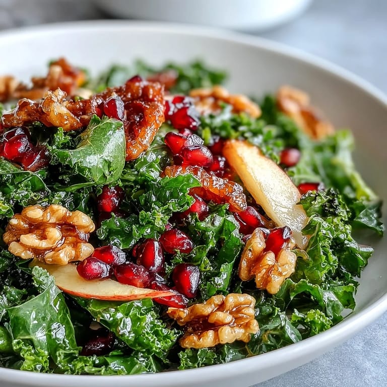 Hearty kale salad with pomegranate arils, crisp apple, and walnuts, drizzled with a zesty apple cider vinaigrette for a nutrient-rich meal.
